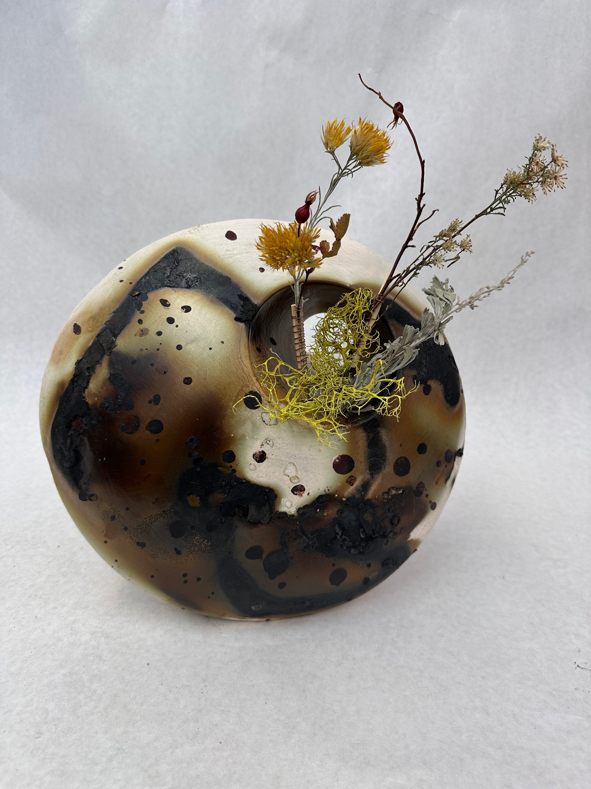 This wall hanging was created using ceramics and a Saggar firing technique that involves placing pottery inside a protective container along with combustible materials.