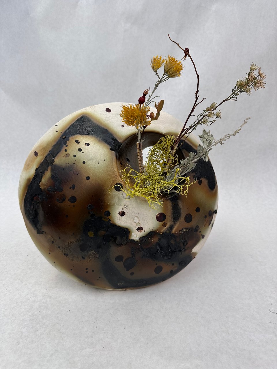 This wall hanging was created using ceramics and a Saggar firing technique that involves placing pottery inside a protective container along with combustible materials.